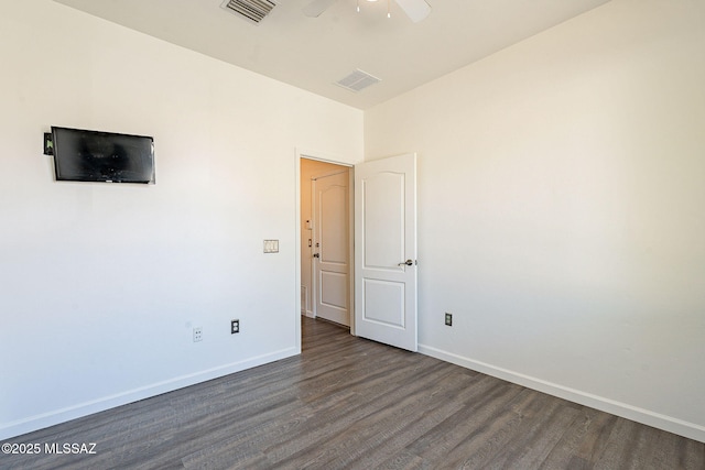 unfurnished room with visible vents, baseboards, and dark wood-style flooring