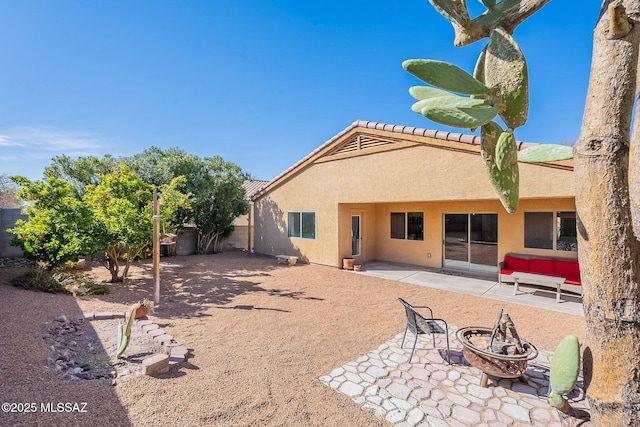 back of property featuring a patio, fence, stucco siding, a fire pit, and a tiled roof