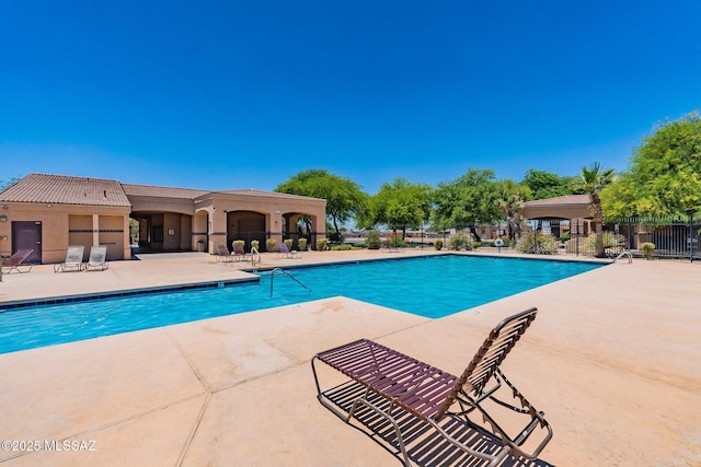 community pool with a patio and fence