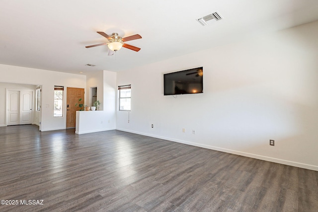 unfurnished living room featuring visible vents, baseboards, ceiling fan, and dark wood-style flooring