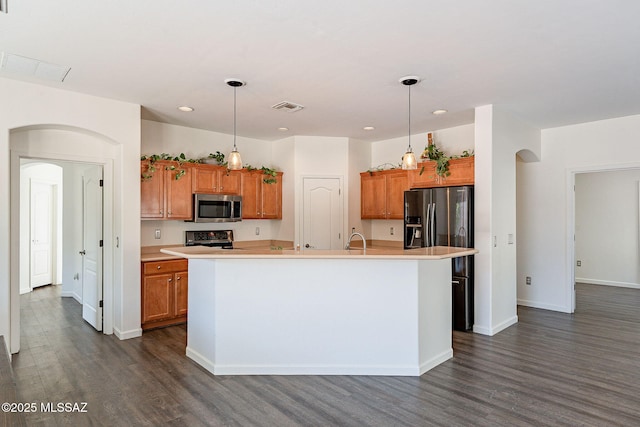 kitchen with brown cabinets, appliances with stainless steel finishes, light countertops, and dark wood-type flooring