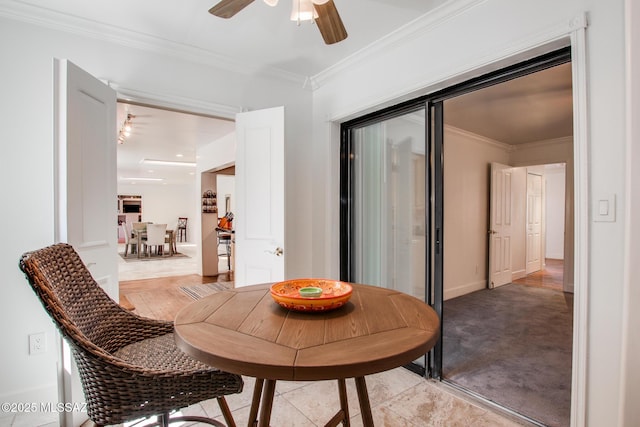 dining area featuring baseboards, light colored carpet, ornamental molding, and a ceiling fan