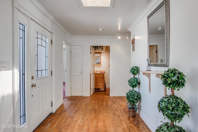 foyer featuring light wood-type flooring, crown molding, and baseboards