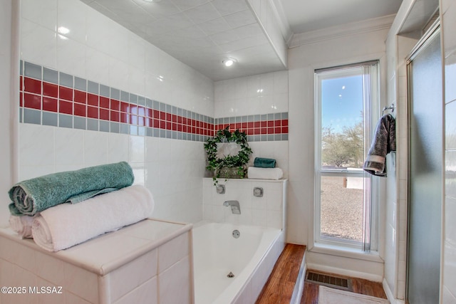 bathroom featuring crown molding, a bath, wood finished floors, and visible vents