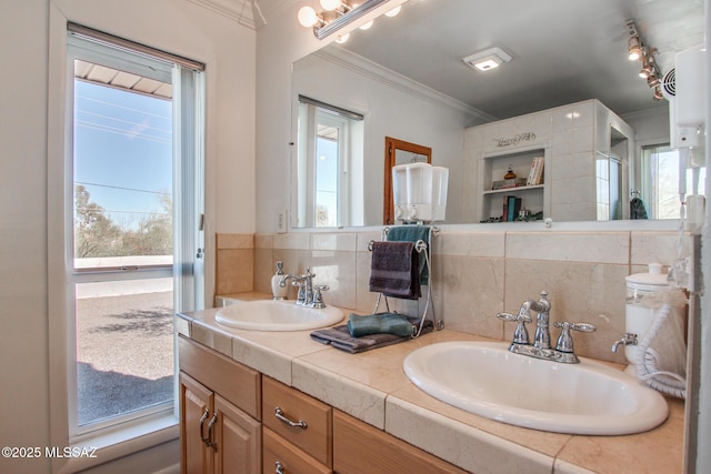 bathroom featuring a wealth of natural light, crown molding, and a sink