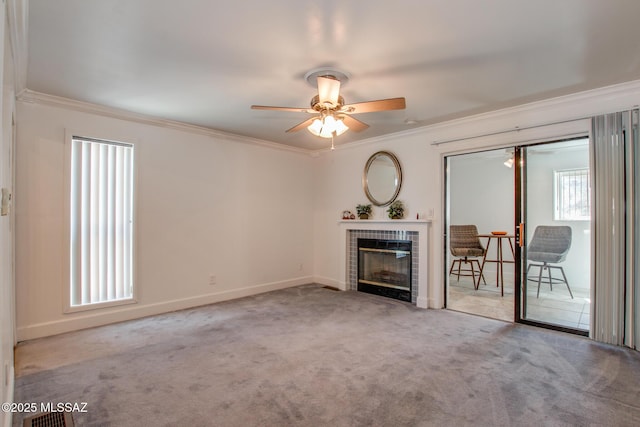 interior space with a tiled fireplace, baseboards, crown molding, and ceiling fan