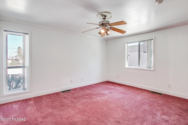 empty room with visible vents, crown molding, baseboards, and carpet floors