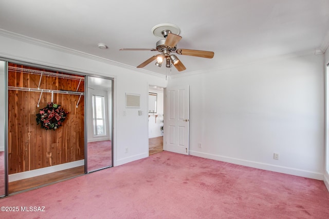 unfurnished bedroom with ornamental molding, a ceiling fan, a closet, carpet flooring, and baseboards