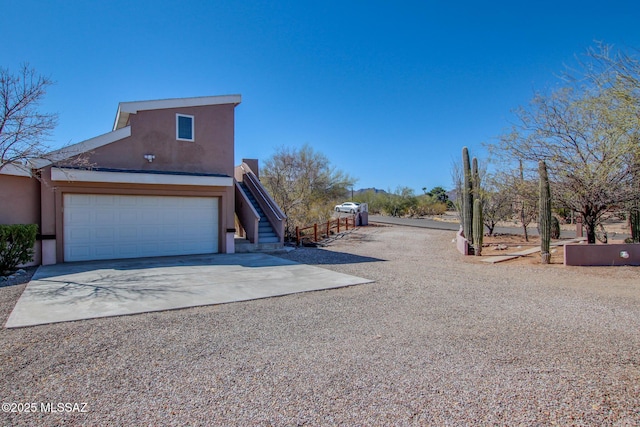 exterior space featuring stairway, stucco siding, driveway, and a garage