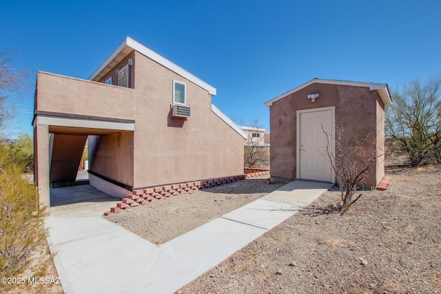 exterior space with a wall mounted air conditioner and stucco siding