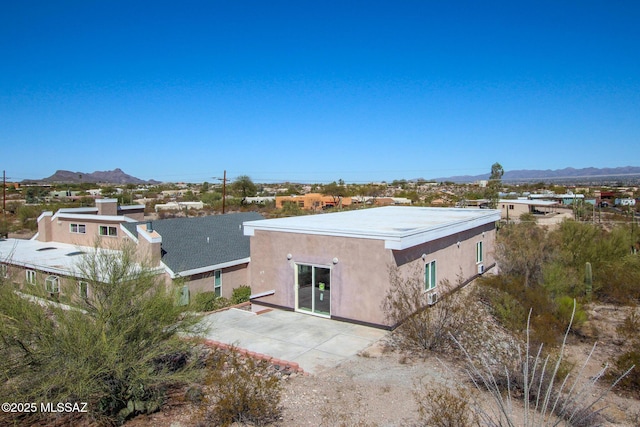 rear view of property with a patio area, stucco siding, and a mountain view