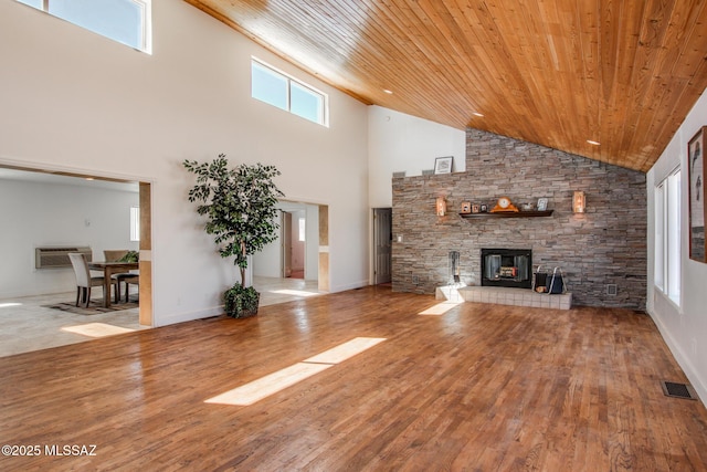 unfurnished living room with visible vents, wood ceiling, an AC wall unit, a fireplace, and wood finished floors