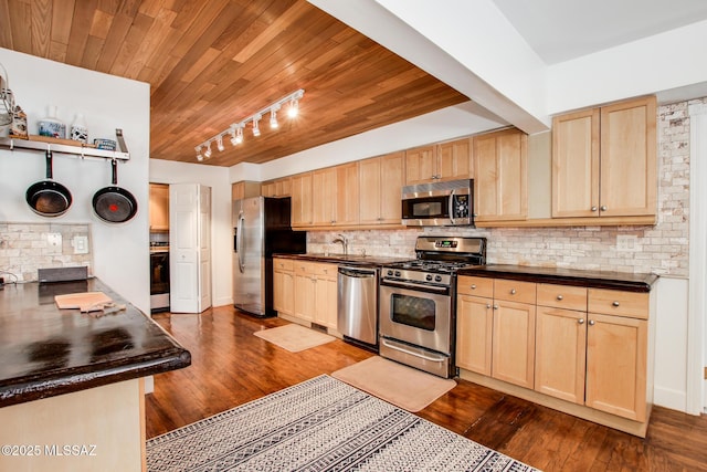 kitchen with dark countertops, light brown cabinetry, and stainless steel appliances