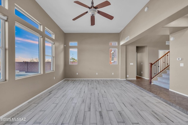 empty room with visible vents, baseboards, stairway, wood finished floors, and a ceiling fan