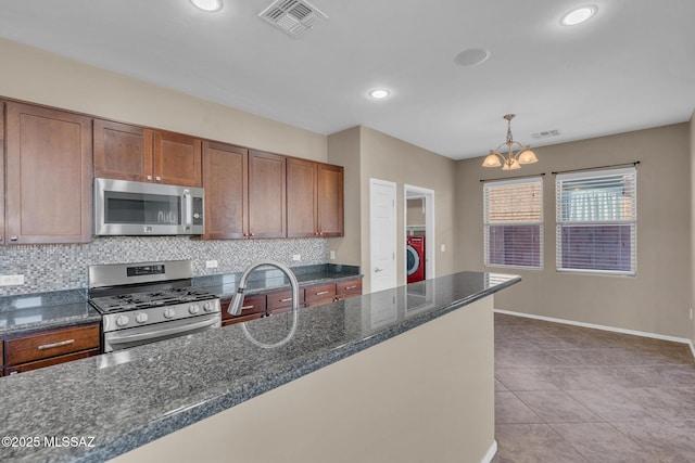 kitchen with visible vents, a notable chandelier, tasteful backsplash, stainless steel appliances, and washer / dryer