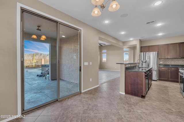 kitchen featuring baseboards, an inviting chandelier, stainless steel appliances, decorative backsplash, and dark countertops