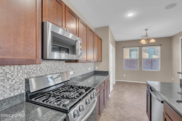 kitchen with backsplash, baseboards, a chandelier, appliances with stainless steel finishes, and brown cabinetry