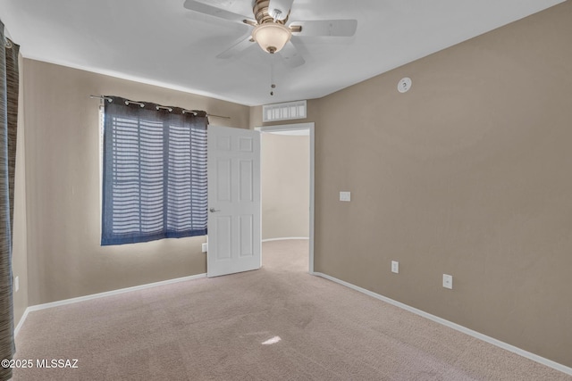 carpeted empty room with visible vents, baseboards, and ceiling fan