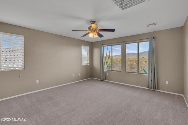 spare room with carpet flooring, visible vents, and ceiling fan