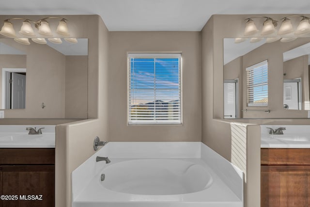 full bath featuring a garden tub, two vanities, and a sink