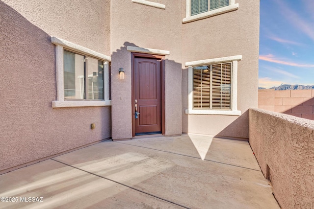 entrance to property with stucco siding and a patio