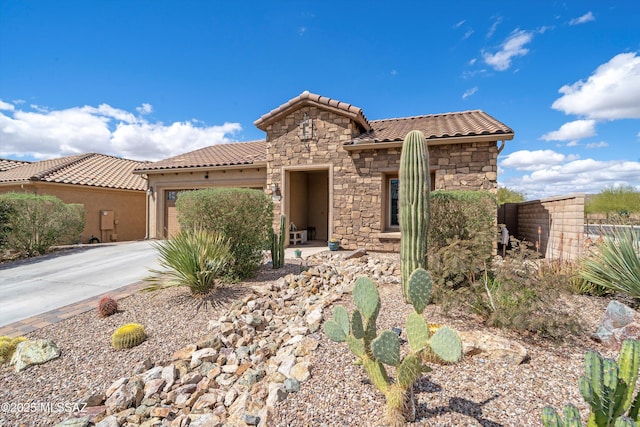 mediterranean / spanish-style home featuring a garage, stone siding, driveway, and a tiled roof