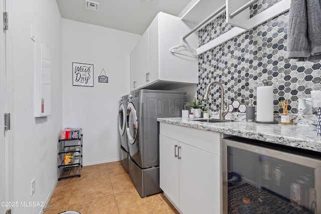 laundry area featuring beverage cooler, visible vents, cabinet space, a sink, and washing machine and dryer