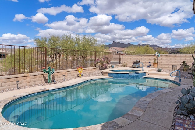 view of pool featuring a mountain view, a pool with connected hot tub, and a fenced backyard