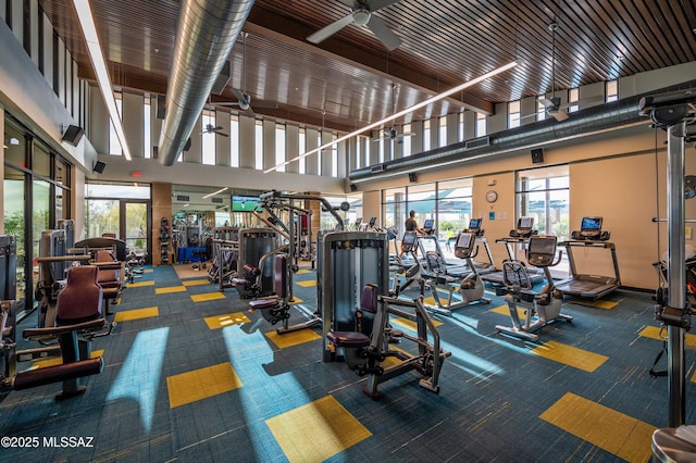 gym featuring ceiling fan and a towering ceiling