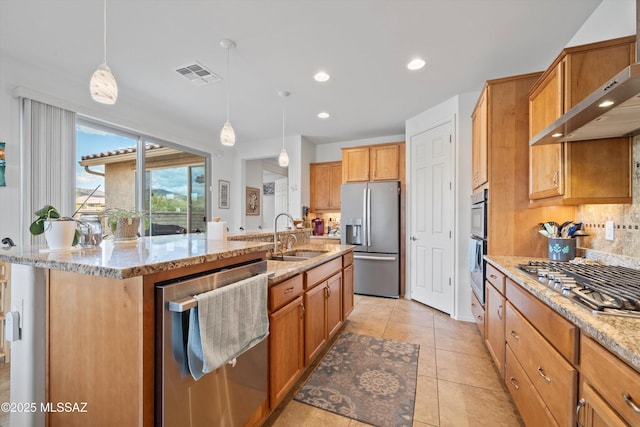 kitchen featuring visible vents, a sink, decorative backsplash, stainless steel appliances, and wall chimney range hood