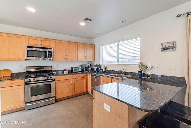 kitchen with visible vents, a peninsula, a sink, appliances with stainless steel finishes, and a kitchen breakfast bar