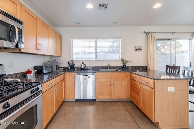 kitchen with visible vents, a breakfast bar, a sink, appliances with stainless steel finishes, and a peninsula