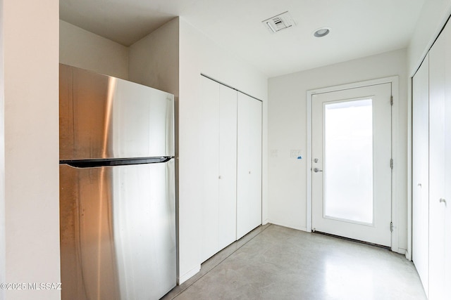 kitchen with visible vents, concrete floors, and freestanding refrigerator