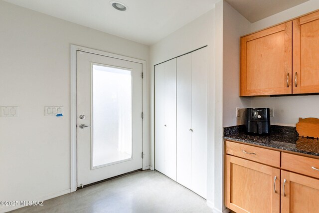 kitchen with dark stone counters and concrete floors