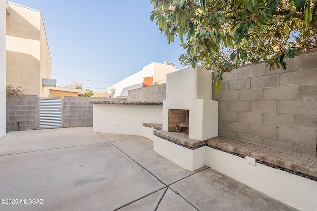 view of patio featuring an outdoor fireplace and fence