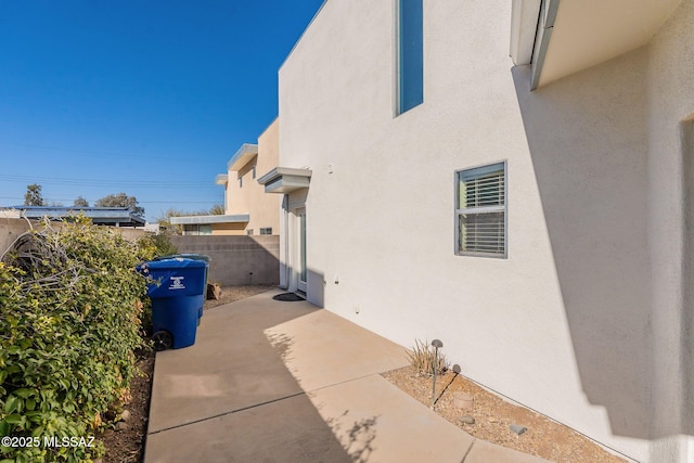view of side of property with a patio area, fence, and stucco siding