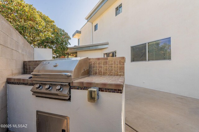 view of patio featuring area for grilling, exterior kitchen, and fence