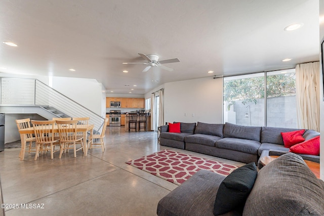 living area with recessed lighting, stairs, concrete flooring, and ceiling fan