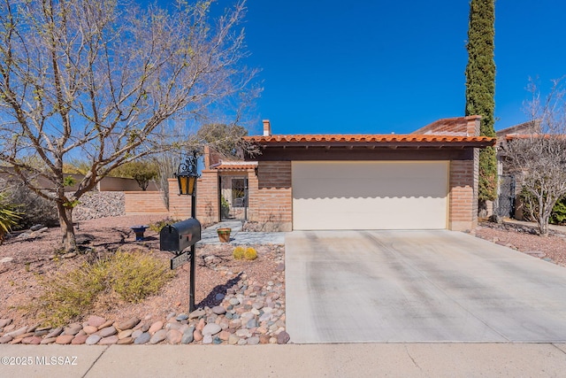 view of front facade with a chimney, a tiled roof, concrete driveway, and a garage