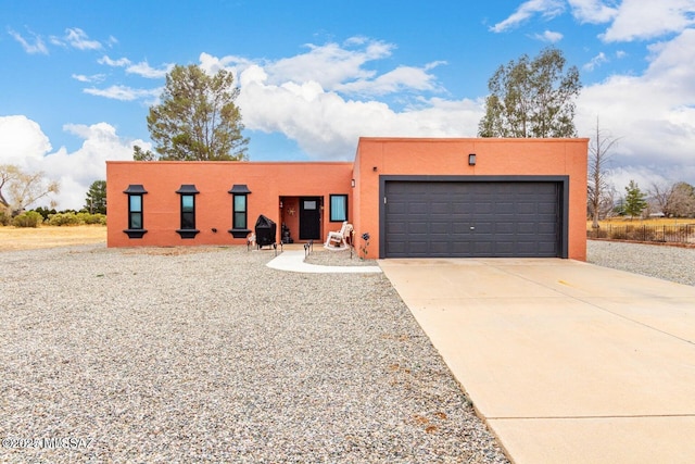 adobe home with a garage, driveway, and stucco siding