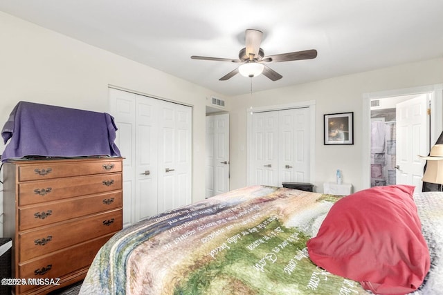 bedroom with visible vents, a ceiling fan, ensuite bathroom, and multiple closets