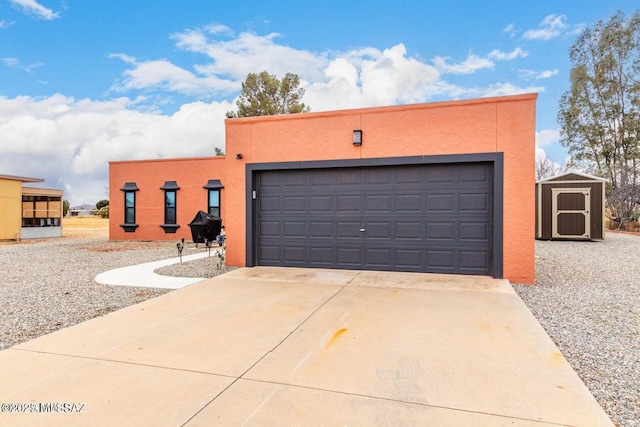 pueblo revival-style home with stucco siding, a garage, an outdoor structure, and driveway