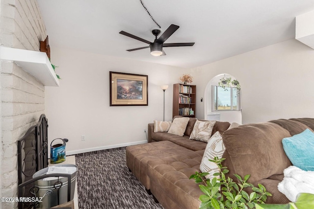 living area with a brick fireplace, baseboards, and a ceiling fan