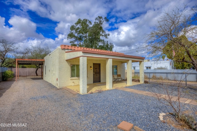 view of front of property featuring a tile roof, fence, and stucco siding