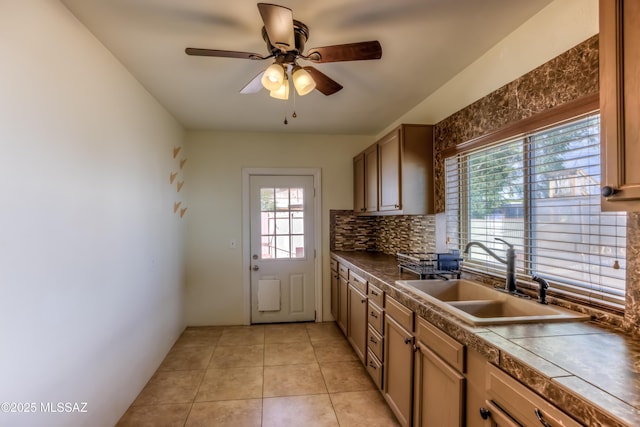 kitchen featuring light tile patterned flooring, ceiling fan, decorative backsplash, a sink, and dark countertops