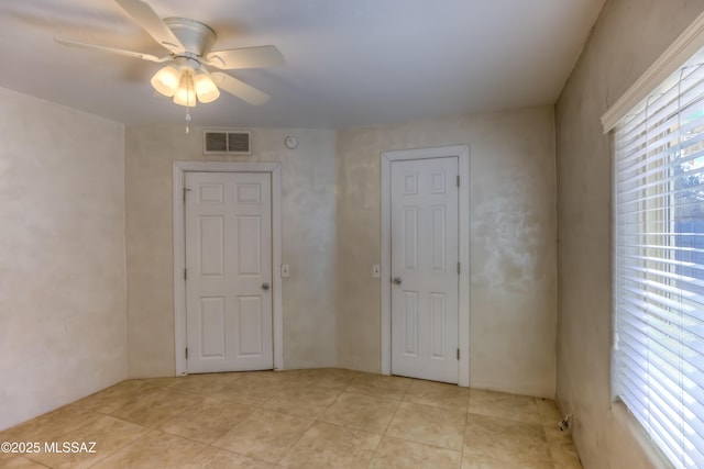 unfurnished room with light tile patterned floors, visible vents, and a ceiling fan