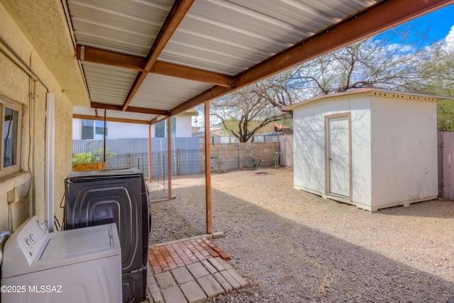 exterior space featuring an outbuilding, independent washer and dryer, a fenced backyard, a storage shed, and a patio area