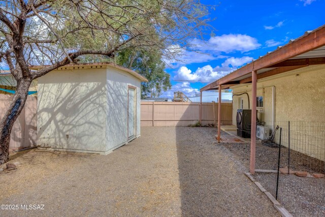 view of yard with a storage shed, a fenced backyard, an outdoor structure, and a patio