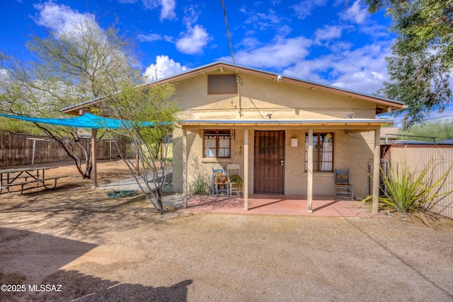 view of front of property featuring a patio area, stucco siding, and fence