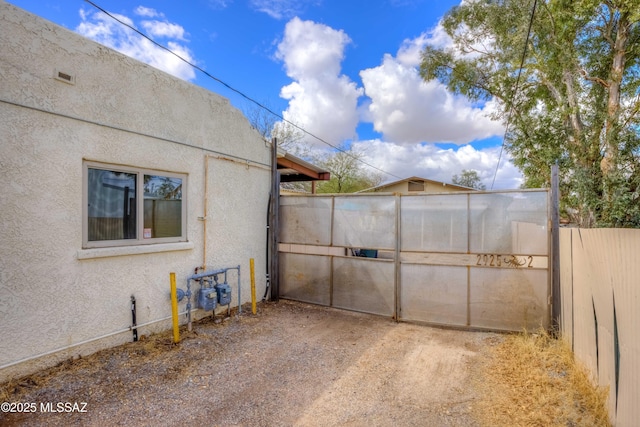 view of home's exterior with a gate, stucco siding, and fence